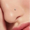 Close-up of a small clear CZ nose stud worn in a nostril