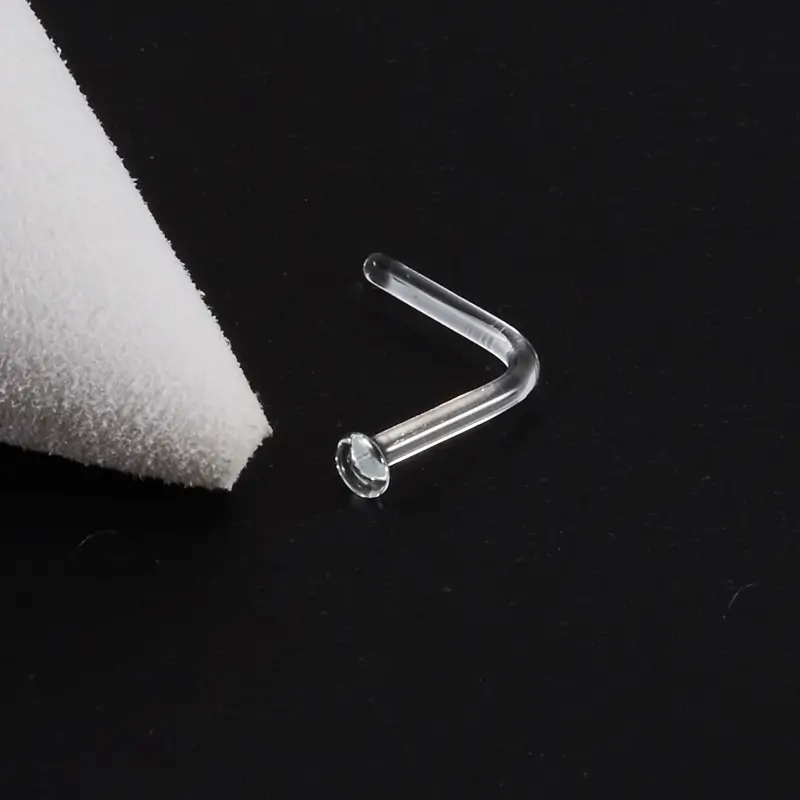 glass-nose-stud-black-background Clear glass L-shaped nose stud on black fabric background