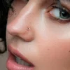 glass-nose-stud-worn-closeup Woman wearing a clear glass L-shaped nose stud in her nostril