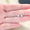 opal-nose-studs-held-in-hand-scale Four posts and two opal tops resting on a hand, showing their small size